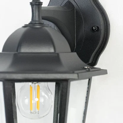 Closeup of classic outdoor wall lantern showing refined black metal detailing and transparent glass panes for clear brightness.