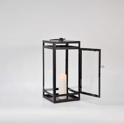 Black metal lantern displayed on white background featuring glass panels open door design and classic decorative lighting appeal.