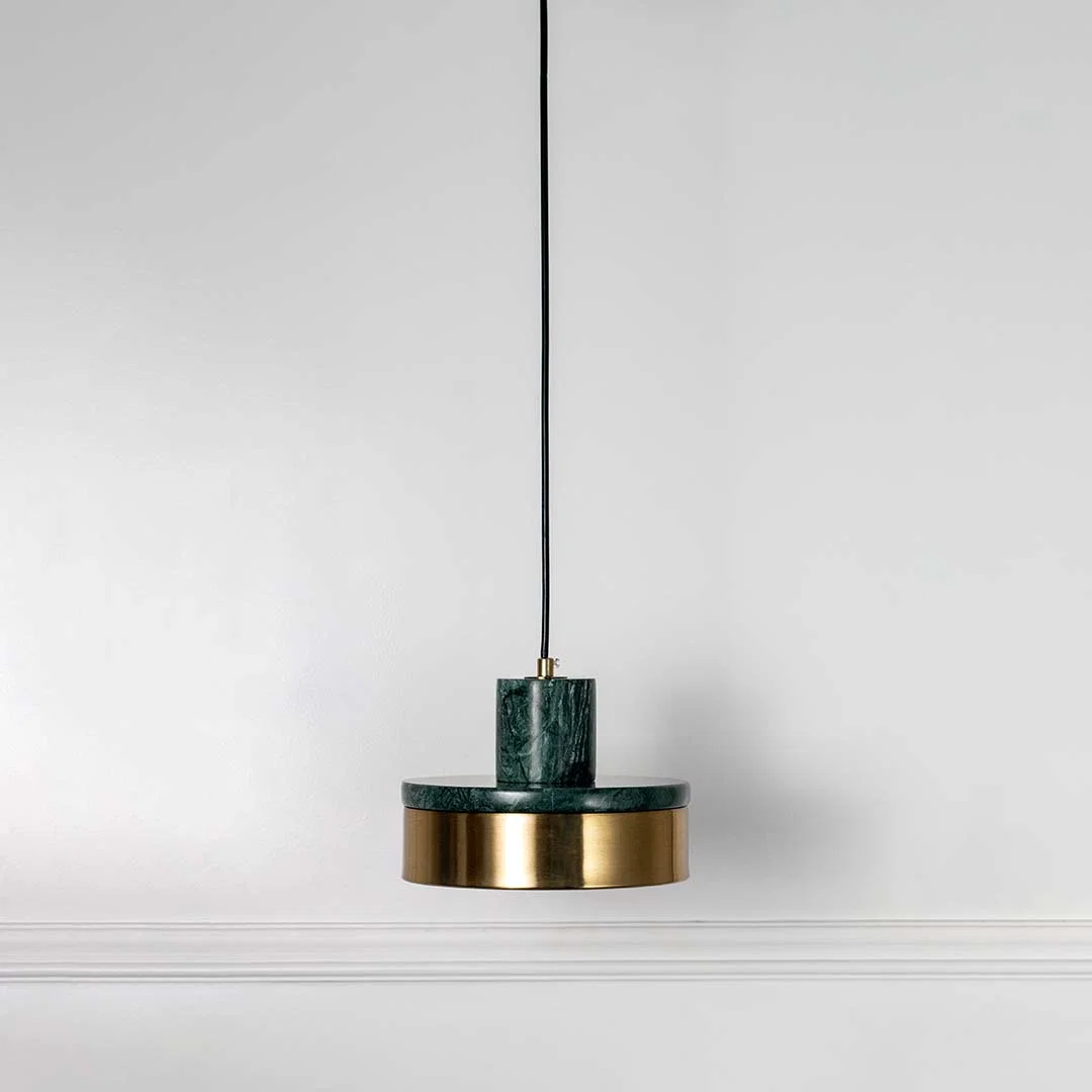 Modern pendant light with green top and gold base hanging against neutral wall background showcasing stylish contemporary lighting decor design.