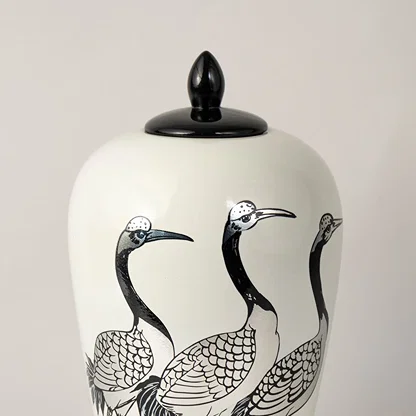 White ceramic decorative jar with black crane artwork and black lid for elegant shelf styling and modern home decor.