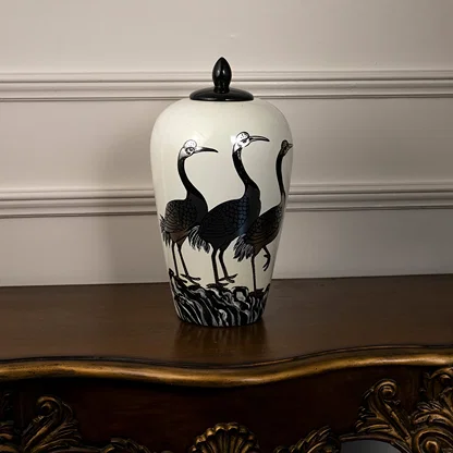 White ceramic decorative jar with black crane artwork displayed on a console table for contemporary home decor settings.