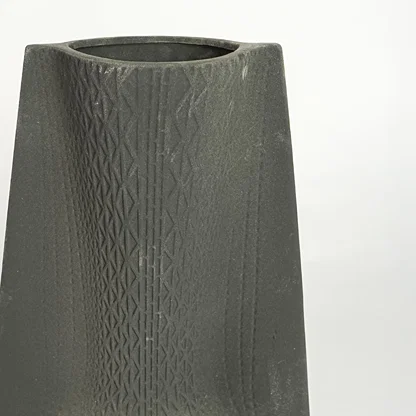 Close up view black textured ceramic vase showing carved surface matte finish decorative ceramic accent for modern home styling.