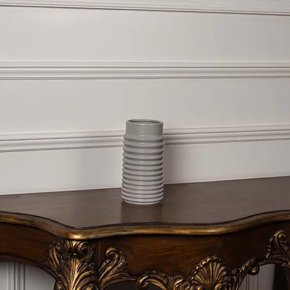 White ribbed ceramic vase styled on a vintage wooden console table adding elegant texture to classic home decor settings.