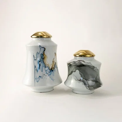 White ceramic jars with bold blue and gray abstract patterns topped with gold lids offering a modern artistic touch perfect for elevating refined tabletop décor.