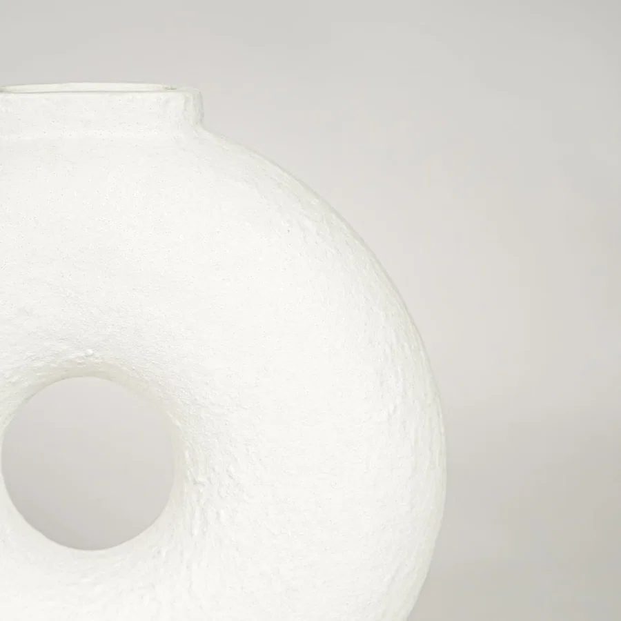 Closeup of matte white ceramic ring vase with sculptural hollow center ideal for minimalist home decor shelf styling.