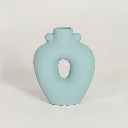 Contemporary light blue ceramic flower vase with abstract cutout shape perfect for entryway table living room decor display.