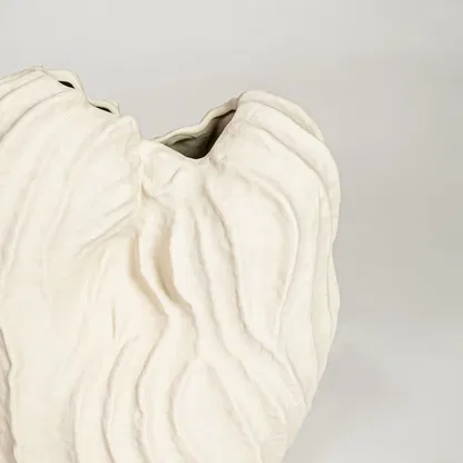 Detailed closeup of white flutter ceramic vase showcasing sculpted curved texture and refined matte surface.