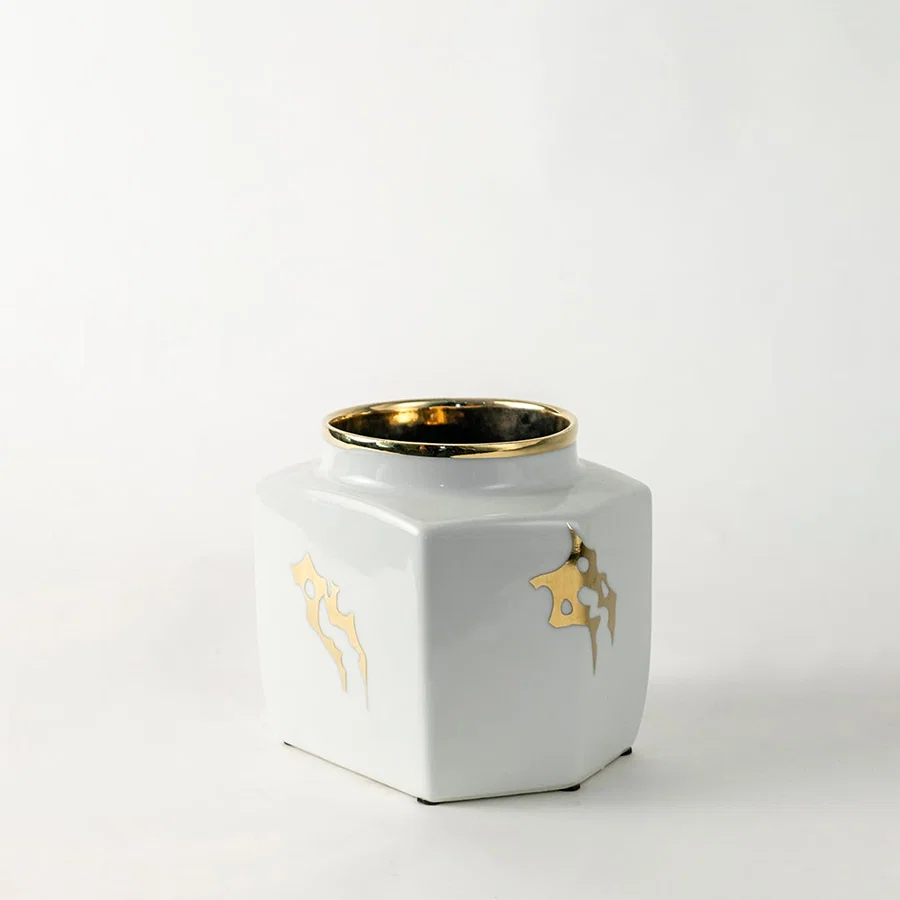 White ceramic decorative storage jar with gold bee artwork and gold rim for elegant shelf styling and home decor.