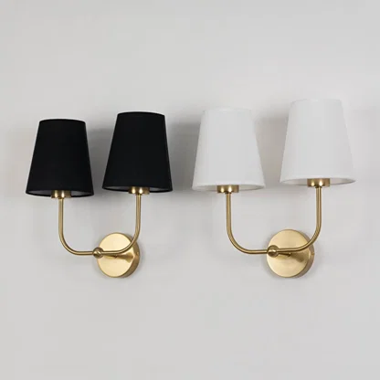 Double wall sconce with gold metal frame and white fabric shades shown on a white background with lights off.