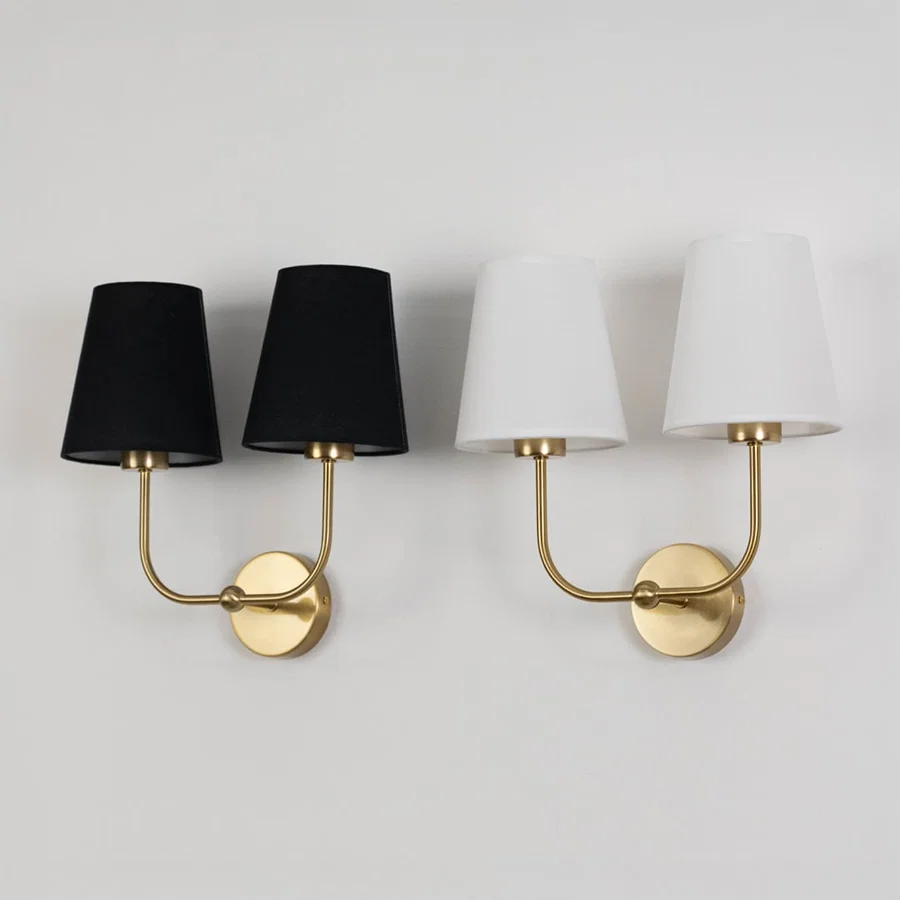 Double wall sconce with gold metal frame and white fabric shades shown on a white background with lights off.