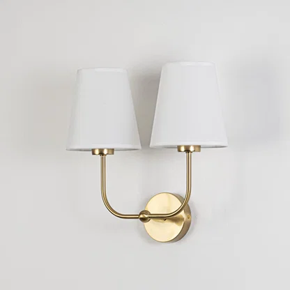 Gold metal double wall sconce with white fabric shades shown on a white background for clear product detailing.