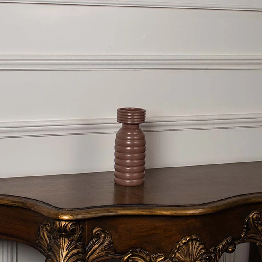 Terracotta brown ceramic column vase with a bold stacked horizontal ribbed pattern displayed on a classic console table.