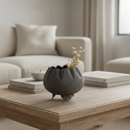 Dark grey textured bowl planter with dried stems on coffee table for elegant modern living room home interior decor.