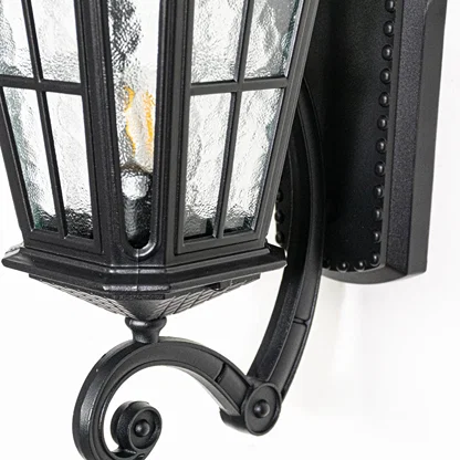 Closeup view of black metal wall lantern highlighting textured glass panels roof detailing and solid outdoor construction.