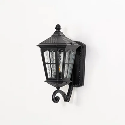 Outdoor wall lantern in black metal switched off on white background highlighting textured glass panels and classic lantern form.