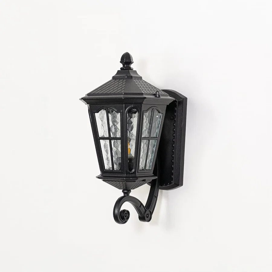 Outdoor wall lantern in black metal switched off on white background highlighting textured glass panels and classic lantern form.