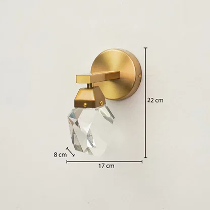 Gold wall-mounted sconce with a faceted clear crystal shade, shown with dimension annotations indicating 22 cm height, 17 cm width, and 8 cm shade depth on a plain light background.
