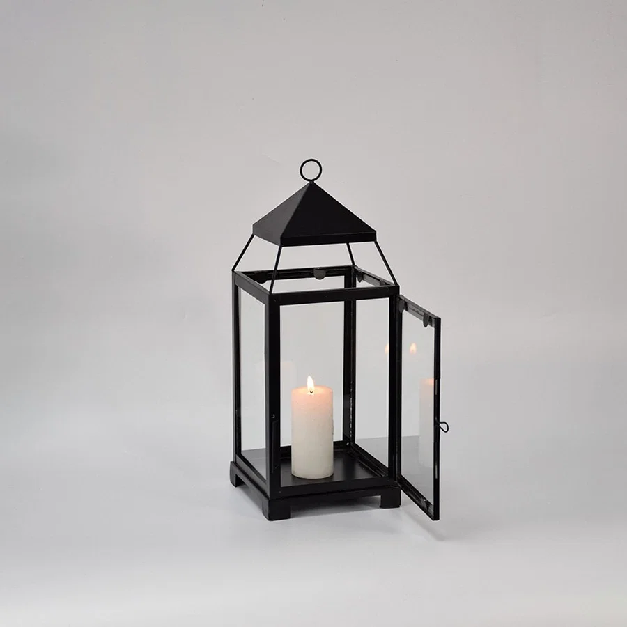 Black metal lantern displayed on white background showcasing clean lines glass panels and timeless decorative lighting design.