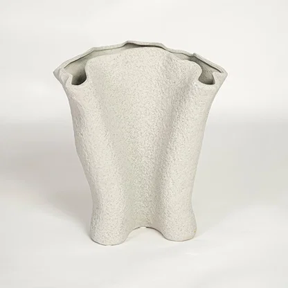 Modern light beige ceramic statement vase with flowing sculptural silhouette for living room console or shelf display.