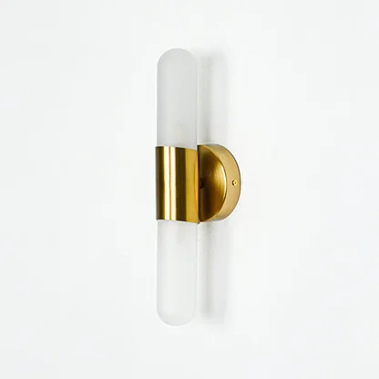 Minimal gold wall sconce with cylindrical frosted glass shade on clean white wall background perfect for contemporary interior decor lighting.