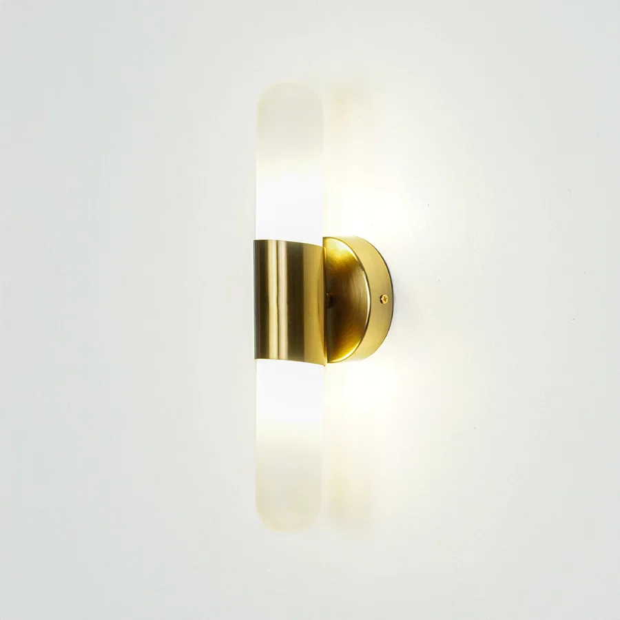 Gold wall light with vertical frosted glass tube mounted on neutral wall background ideal for modern bedroom or hallway lighting.