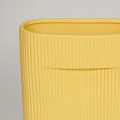 Closeup of mustard ceramic vase with ribbed textured finish for elegant shelf and tabletop decor styling ideas.