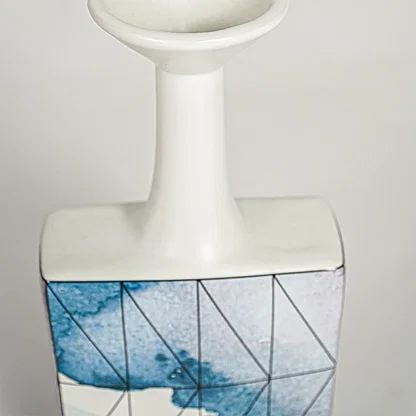 Closeup image of white ceramic bottle vase with abstract blue artwork for elegant console table decor styling.