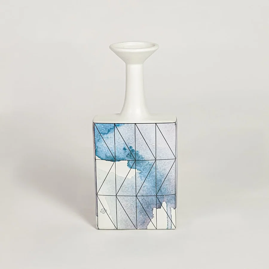 Blue glass bottle vase for modern shelf placement and elegant indoor home decor styling accent piece.