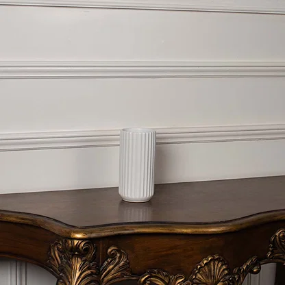 White ribbed ceramic vase displayed on a plain white background showing its clean cylindrical shape and simple modern texture.