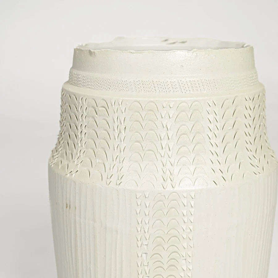 Close view of white ceramic textured vase featuring intricate surface pattern and elegant handcrafted detailing.