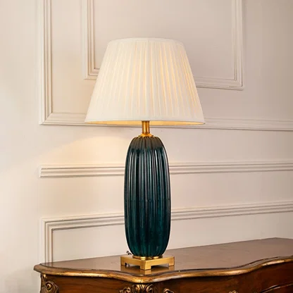 Blue ribbed glass table lamp with pleated shade casting warm ambient light for stylish interior decor settings.
