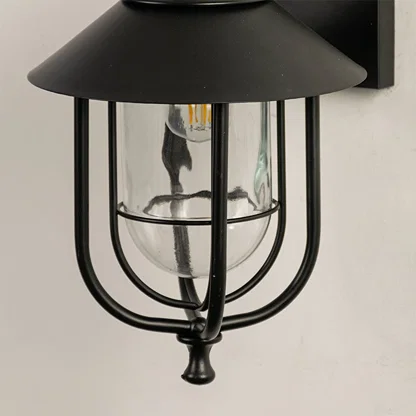Close view of the black outdoor lantern showing detailed metal curves clear glass housing and refined modern finish.