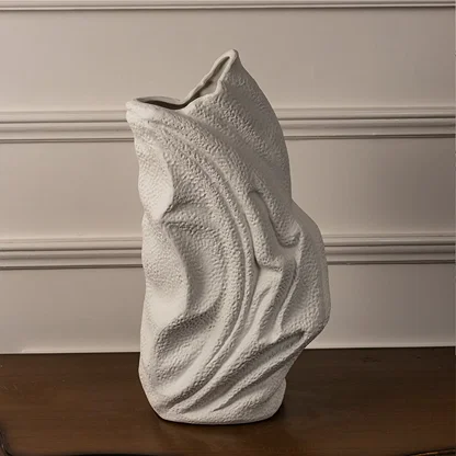 White ceramic textured vase with artistic wavy surface placed on white background for elegant modern home decor.