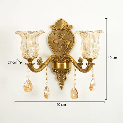 An ornate two-light wall sconce with a gold-toned metal frame, clear ribbed glass shades, and hanging crystal teardrop drops, shown with dimension labels indicating 40 cm width, 40 cm height, and 27 cm shade-to-center spacing on a white background.