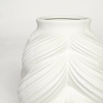 Close view of white ceramic sculpted vase highlighting layered leaf pattern and smooth matte finish.