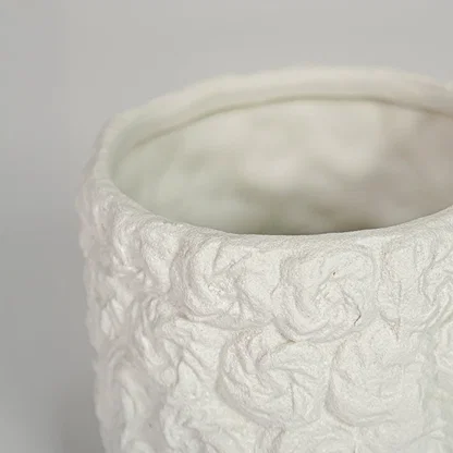 Closeup of white ceramic decorative vase with handcrafted textured interior highlighting refined artisanal craftsmanship.