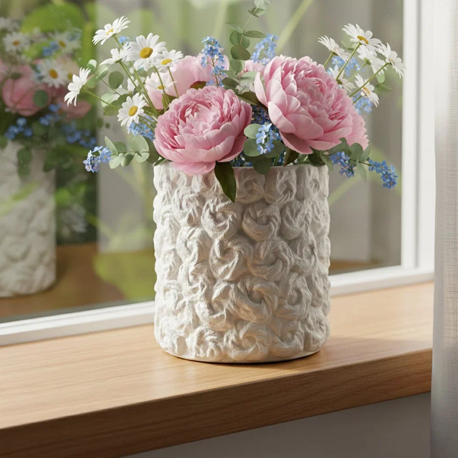White ceramic decorative vase styled with pink flowers on a wooden table for elegant modern home decor settings.