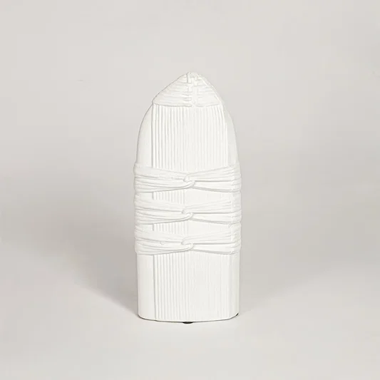 White ceramic sculpted decorative vase with vertical ribbed detailing isolated on white background for elegant home decor use.