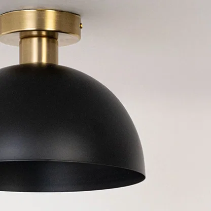 Closeup of black ceiling light with gold base and dome shade for elegant modern ceiling lighting and home interior decor.