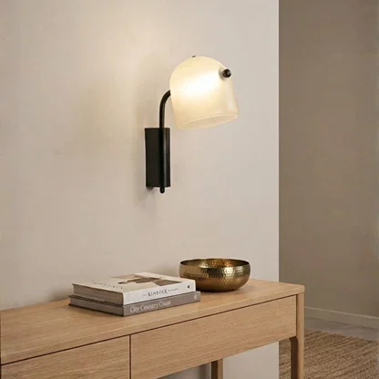Minimalist black metal arm frosted glass dome wall sconce light over a wooden console table for modern entryway home decor.