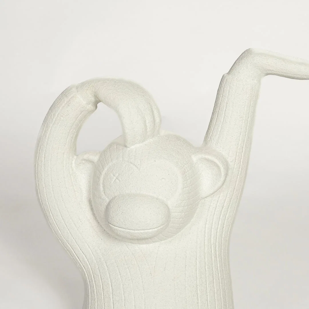 Close up of white monkey sculpture showing carved texture facial detail and raised arm design modern artistic decor piece.