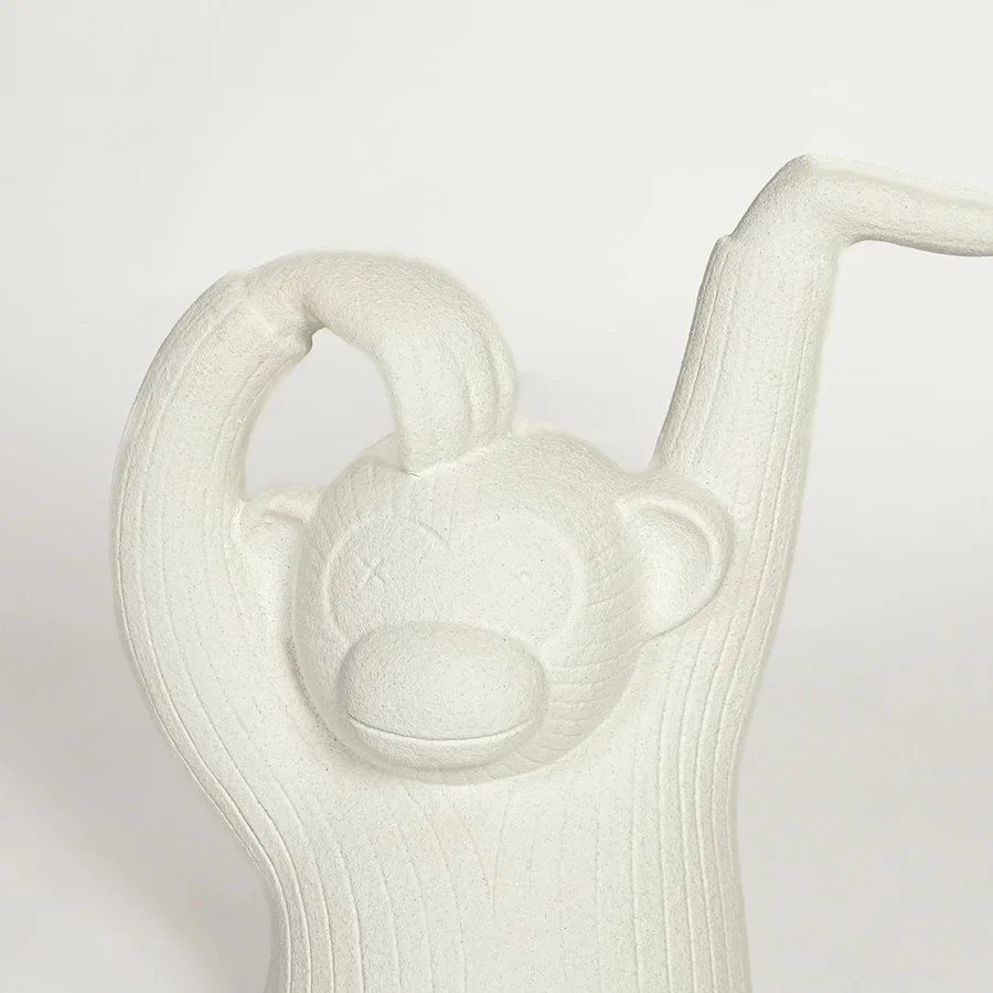 Close up of white monkey sculpture showing carved texture facial detail and raised arm design modern artistic decor piece.