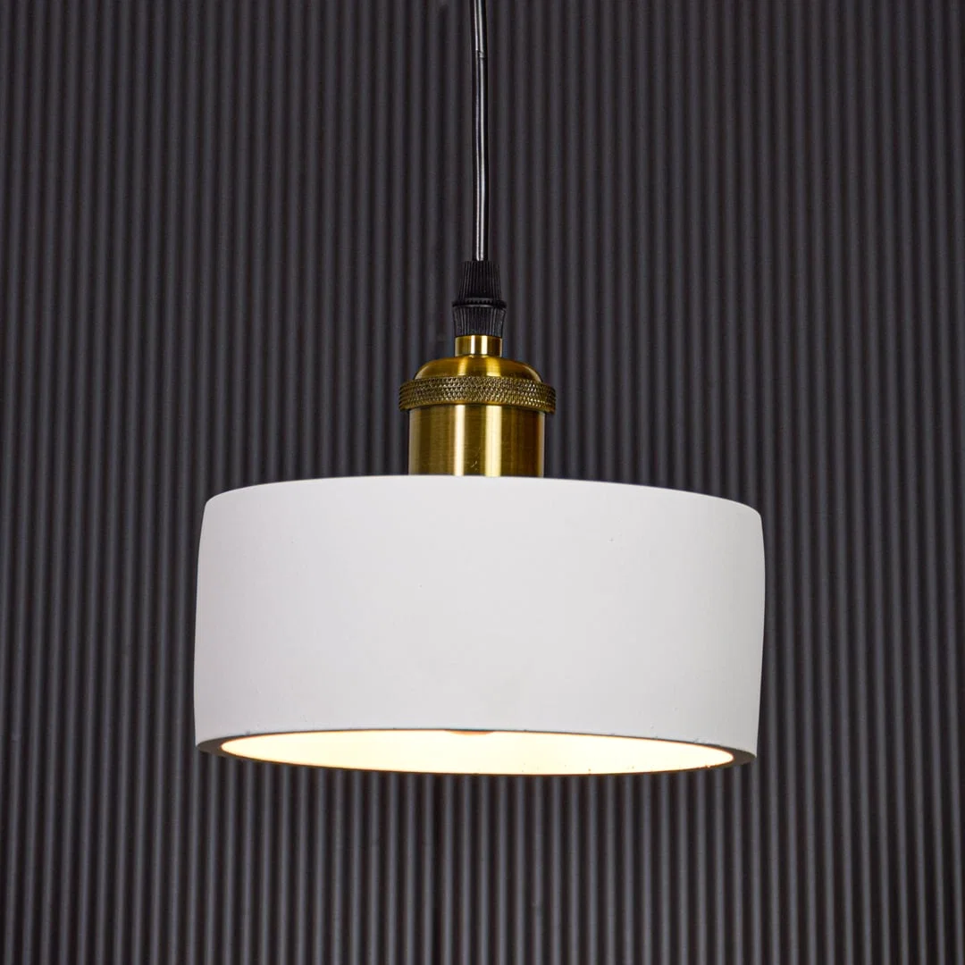 White metal pendant light with gold holder switched on against black background creating focused modern ambient lighting.