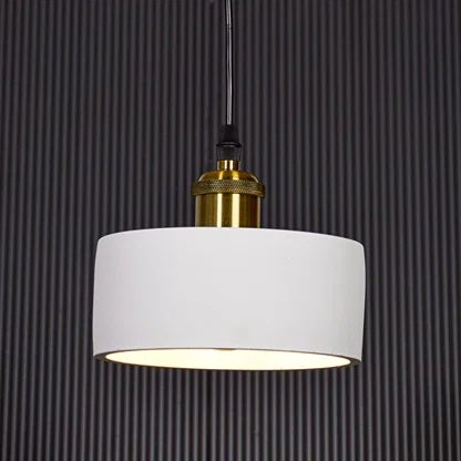 White metal pendant light with gold holder switched on against black background creating focused modern ambient lighting.