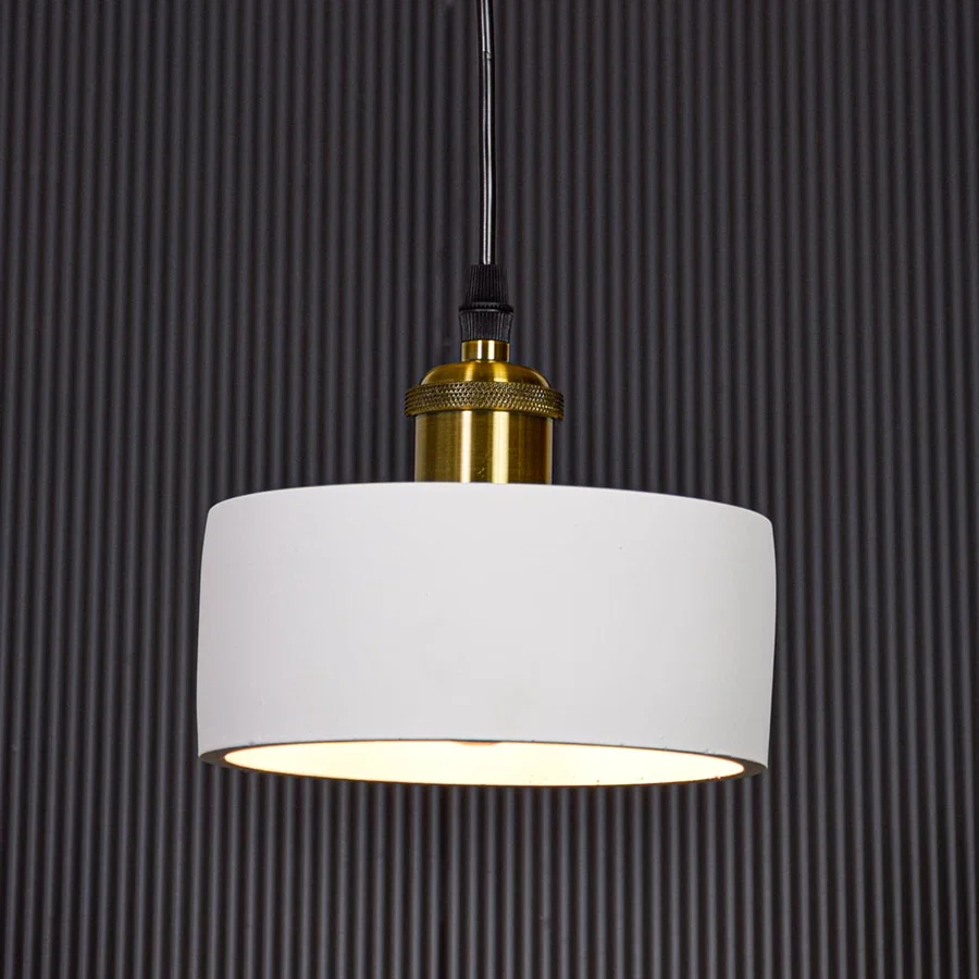 White metal pendant light with gold holder switched on against black background creating focused modern ambient lighting.