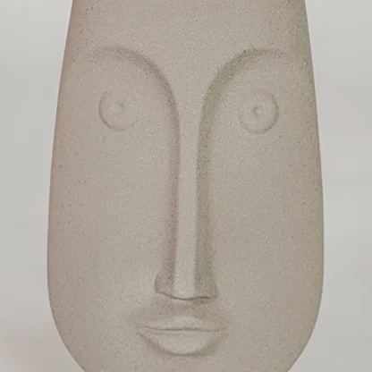 Closeup image of beige ceramic abstract face sculpture for modern shelf decor styling with matte finish display.