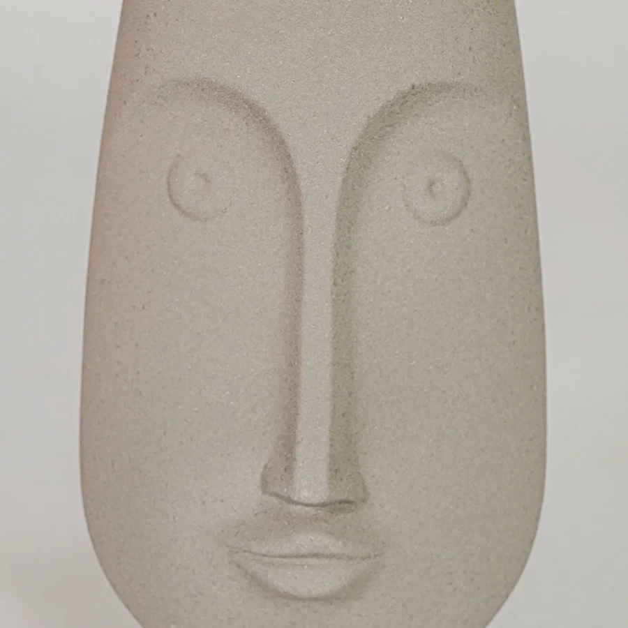 Closeup image of beige ceramic abstract face sculpture for modern shelf decor styling with matte finish display.