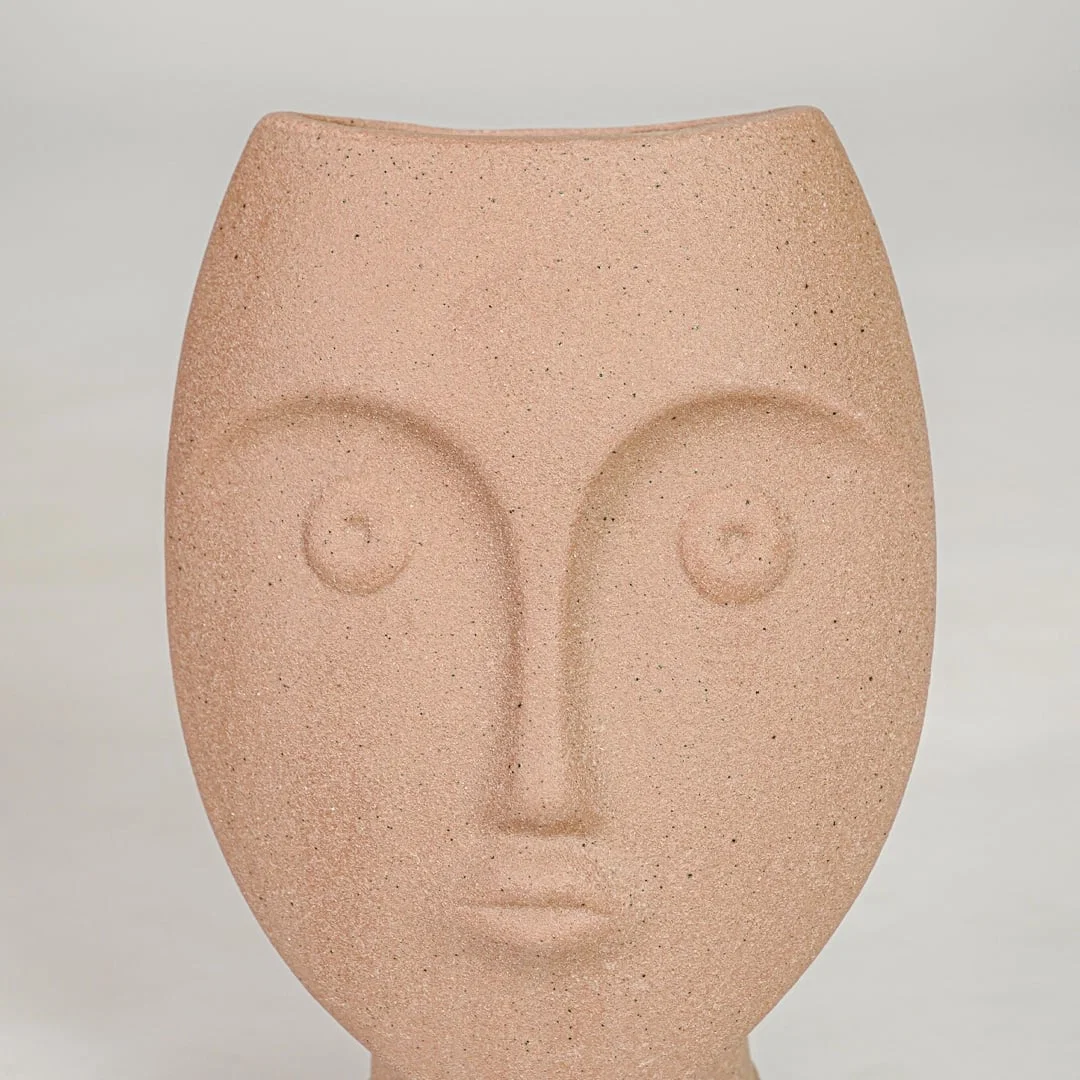 Closeup image of peach ceramic face decor sculpture for modern tabletop styling with artistic matte texture finish.