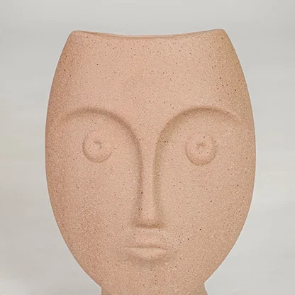 Closeup image of peach ceramic face decor sculpture for modern tabletop styling with artistic matte texture finish.