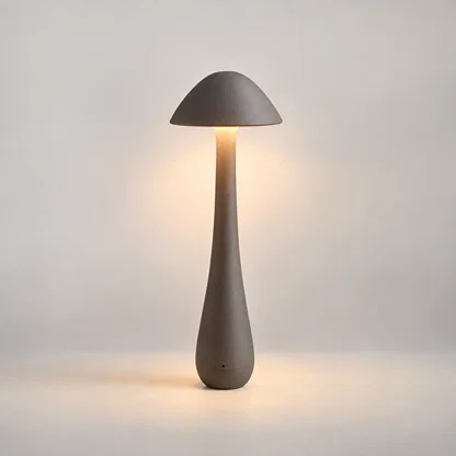 A mushroom-shaped table lamp with a matte gray concrete-like finish, shown lit against a soft neutral background.